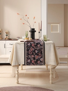 Detail of black table runner with vibrant paisley floral pattern on beige tablecloth