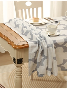 Detail showing thick polyester tablecloth with clover pattern draped over a wooden table