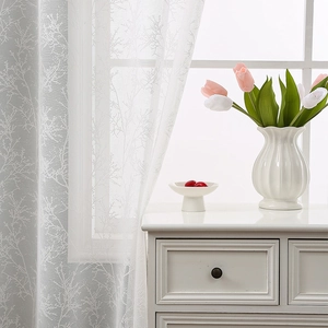 Minimalist white lace curtain with branch patterns hanging in a bright Nordic living room