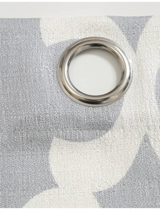Dettaglio di tessuto a motivi floreali grigi con occhiello metallico per tende