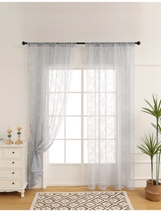 Detail of light blue-grey lace curtain featuring floral embroidery and wavy scalloped edges