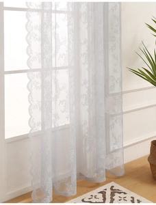 Close-up of white floral lace curtain with scallop edges and mesh polyester texture