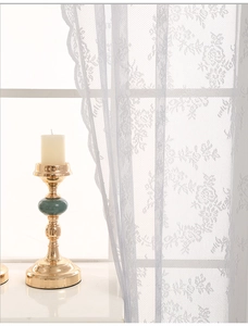 Detail of white sheer lace curtain with rose floral embroidery and wavy scalloped edges