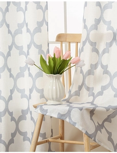 Detail of white linen curtain with grey gourd pattern draped over a wooden dining chair