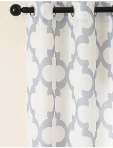 Detail of white curtain with grey quatrefoil pattern and silver metal grommets