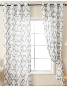 Detail of white trellis pattern curtains with metal grommets in a warm living room