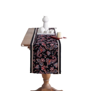 Black table runner with colorful paisley floral patterns on a wooden dining table