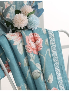 Detail of floral printed curtains with pink roses on a textured linen light blue fabric