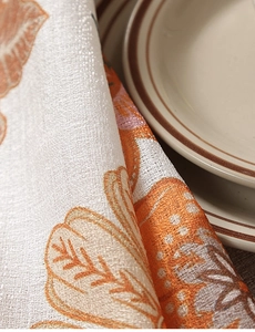 Close-up of thick textured linen tablecloth with orange pumpkin prints for fall decor