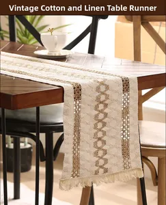 Detail of hollowed-out crochet table runner with fringes and striped linen texture