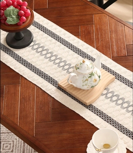 Detail of woven table runner with gray circular patterns on a dark wood table