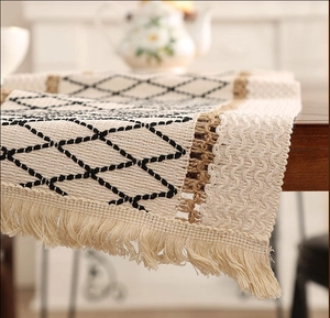Close-up of cream linen table runner with black diamond embroidery and tassels