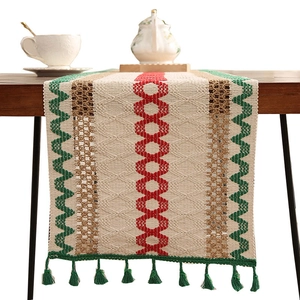 Bohemian striped table runner with geometric woven patterns and tassels on wooden desk