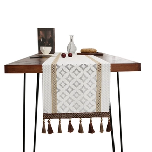 Modern white lace table runner with geometric weave patterns and tassel fringe details