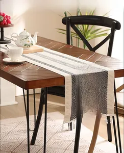Détail d'un chemin de table en lin kaki à rayures avec des motifs tissés et des franges