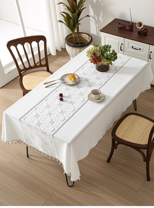 Detail of white lace tablecloth with hollow crochet floral pattern and beige tassel edges