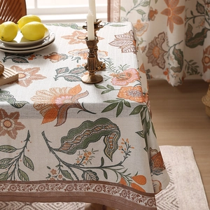 Modern minimalist tablecloth with orange floral prints and green leaves on wood table