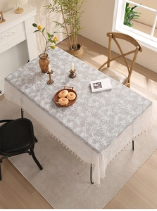 Close-up of grey tablecloth featuring white branch patterns and white lace tassels