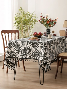Close-up of tropical palm leaf print and black tassel fringe on cotton linen tablecloth