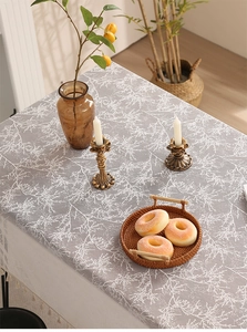 Detail of gray linen tablecloth with white leaf patterns and beige tassel fringe