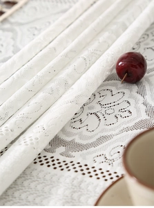 Detailed close-up of white floral lace embroidery on high-quality thick tablecloth fabric