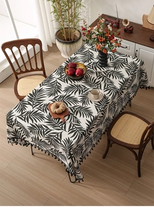 Close-up of Nordic style linen tablecloth with black leaf print and decorative fringe