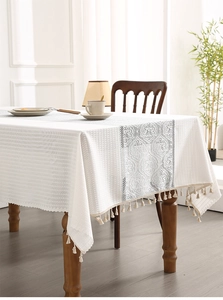 Detailed view of white fabric tablecloth with lace embroidery and elegant tassels