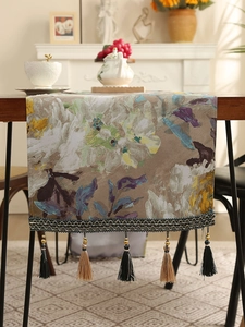 Close-up of artistic abstract floral table runner with decorative tassels and golden beads