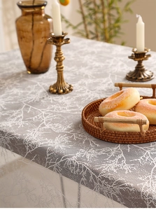 Close-up of semi-transparent grey lace tablecloth with delicate white tree patterns