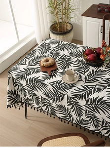 Detailed view of Nordic linen tablecloth with black leaf prints and delicate fringe edges