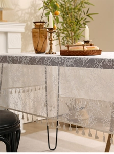 Detail of white lace tablecloth showing tree branch patterns and fringe tassel accents
