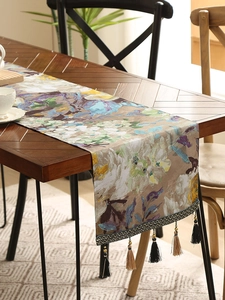 Close-up of abstract floral table runner featuring purple oil painting and woven fringe tassels