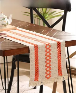 Détail de chemin de table en lin kaki rétro avec motifs losanges orange et des franges
