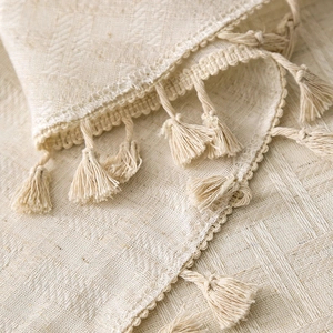 Elegant off-white linen round tablecloth with decorative tassel edges and natural texture