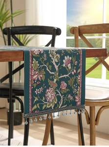 Dettaglio del runner da tavolo verde scuro con motivi floreali e nappe di perle blu