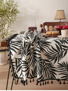 Detail of Nordic palm leaf print tablecloth featuring black tassels and linen texture