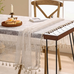 Elegant white lace table runner with branch hollow pattern and fringe tassels on wood table