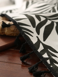 Detailed macro view of Nordic linen tablecloth with black leaf print and fringe tassels