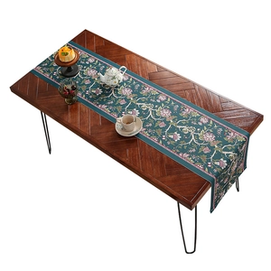 Runner da tavolo vintage verde scuro con motivi floreali su un tavolo da pranzo in legno rustico
