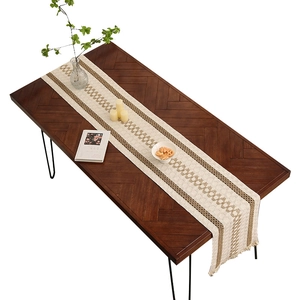 Chemin de table tissé beige et marron à motifs géométriques et franges sur table en bois