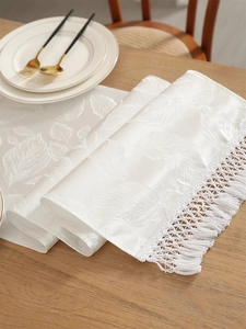 Macro shot of white silk texture table runner with leaf veins and fringe details