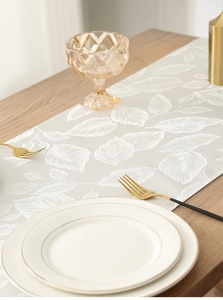 Detail of grey satin table runner with white leaf jacquard and elegant silk texture