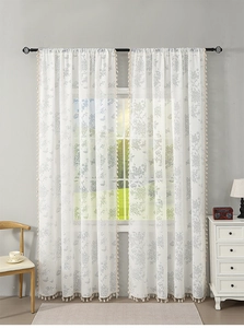 Detail of white lace sheer curtains featuring grey rose patterns and beige tassel trim