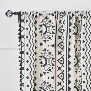 Dettaglio di tenda in cotone e lino con stampe geometriche nere e bordi con nappe