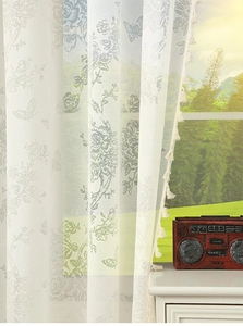 Detail of French butterfly lace curtain with floral patterns and soft tassel fringe
