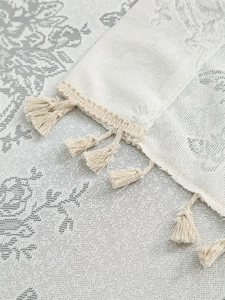 Close-up of cream white jacquard lace curtain with floral patterns and fringe tassels