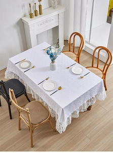 Close-up of elegant white rectangular tablecloth with delicate lace borders and leaf patterns