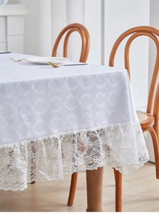 Close-up of white linen tablecloth featuring leaf jacquard and elegant crochet lace trim