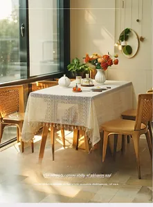 Close-up of beige hollow lace tablecloth with elegant floral patterns and tassel edge detail