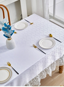Close-up of white tablecloth with leaf textures and elegant lace border detailing
